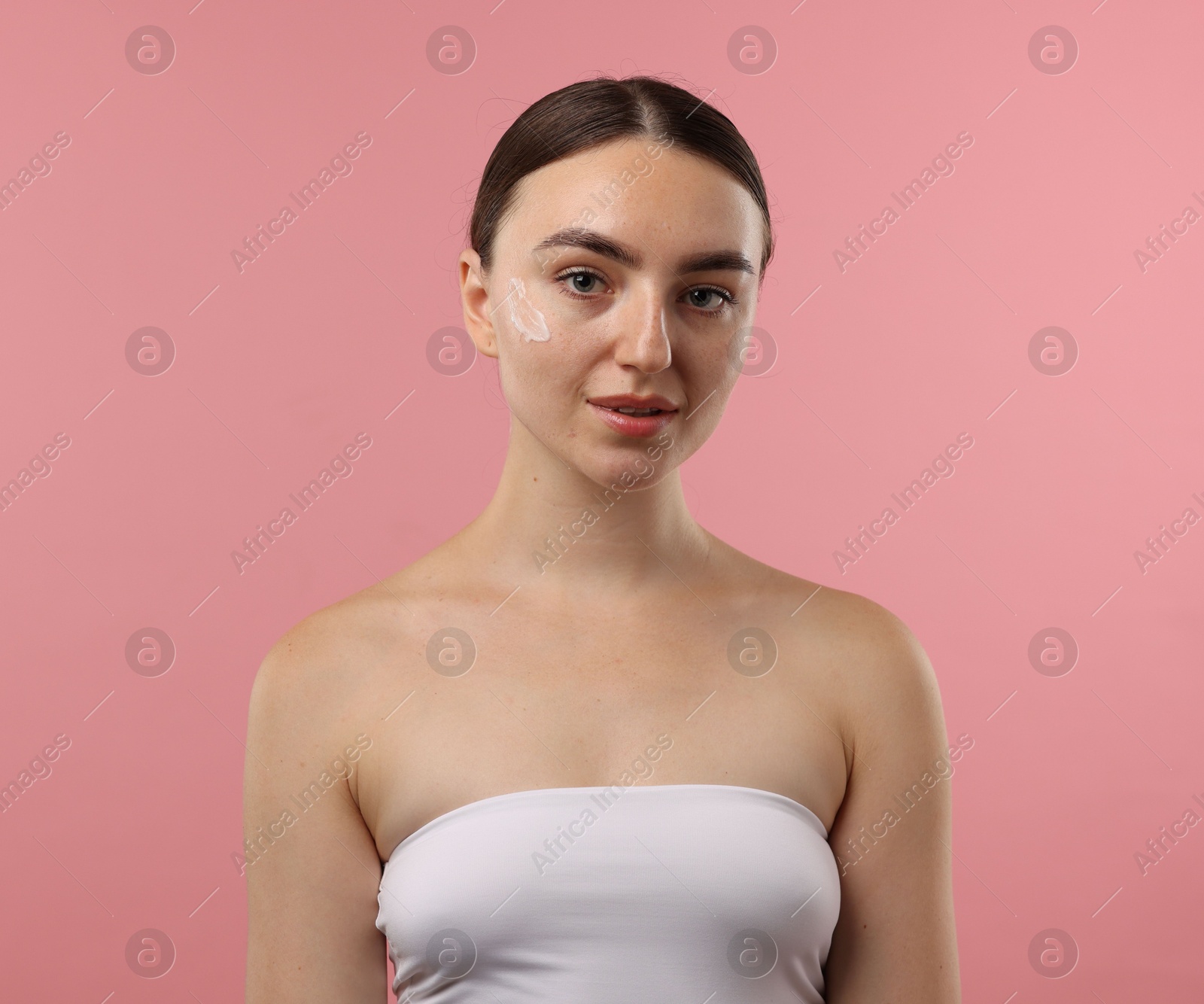 Photo of Beautiful woman with cream on her face against pink background