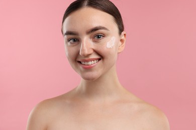 Photo of Beautiful woman with cream on her face against pink background, closeup
