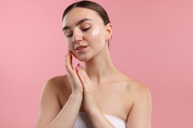Photo of Beautiful woman with cream on her face against pink background