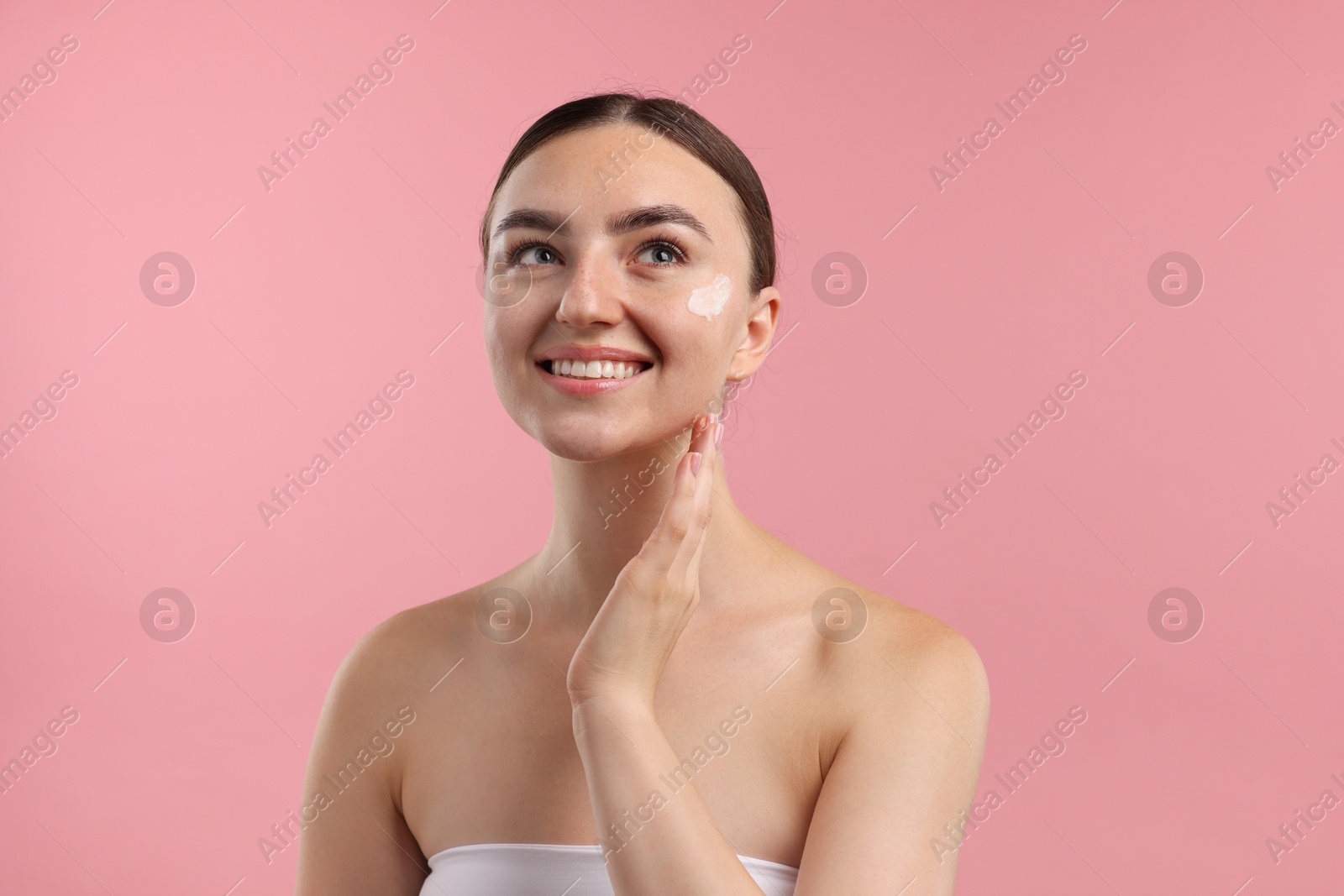 Photo of Beautiful woman with cream on her face against pink background