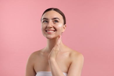 Photo of Beautiful woman with cream on her face against pink background