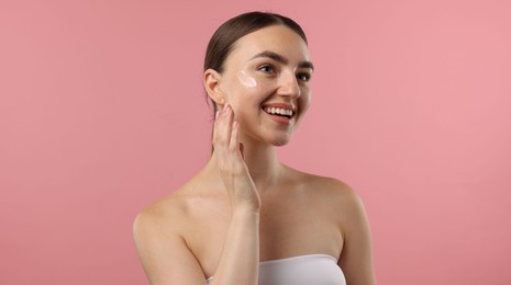 Photo of Beautiful woman with cream on her face against pink background
