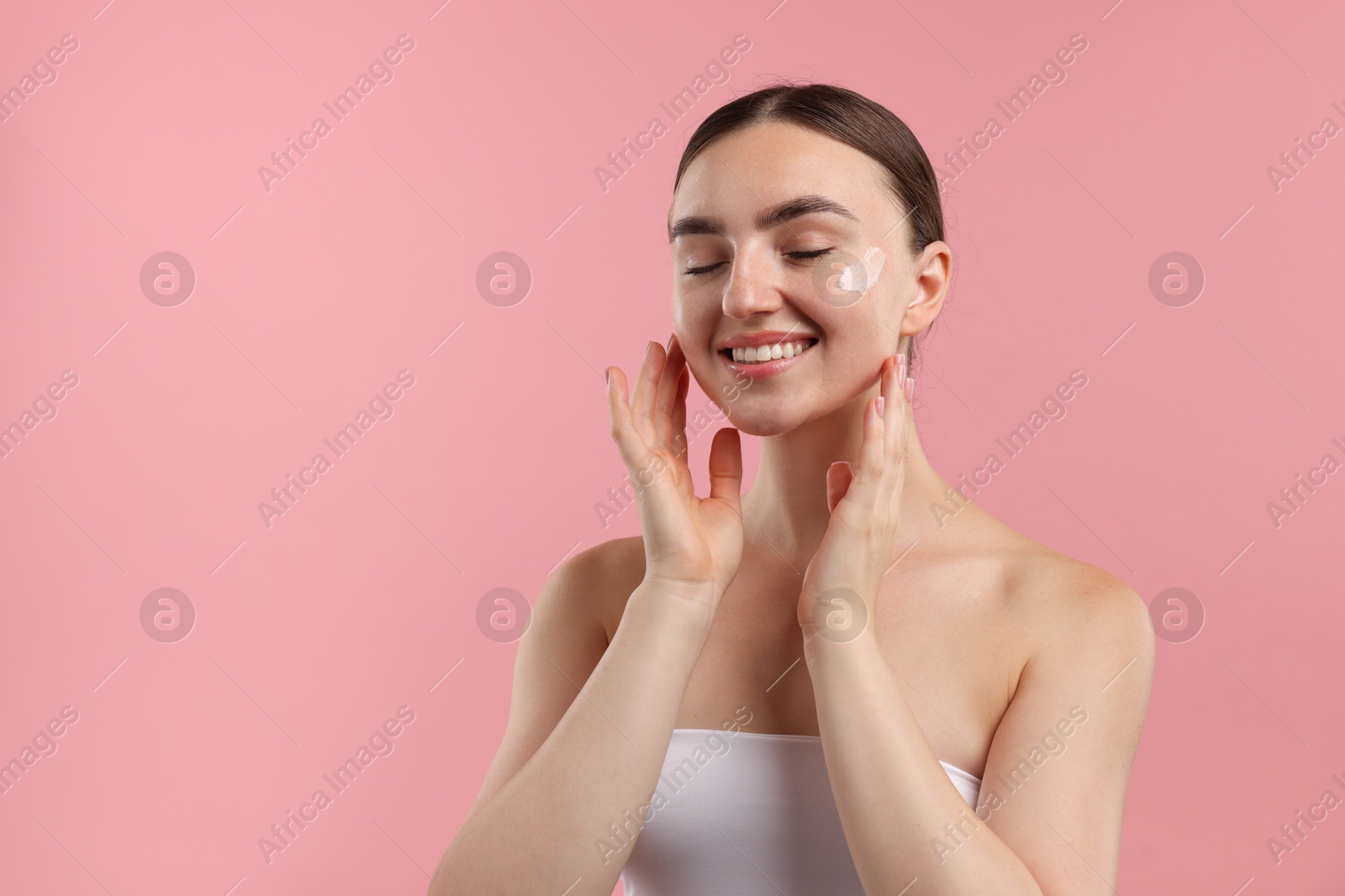 Photo of Beautiful woman with cream on her face against pink background