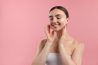 Photo of Beautiful woman with cream on her face against pink background