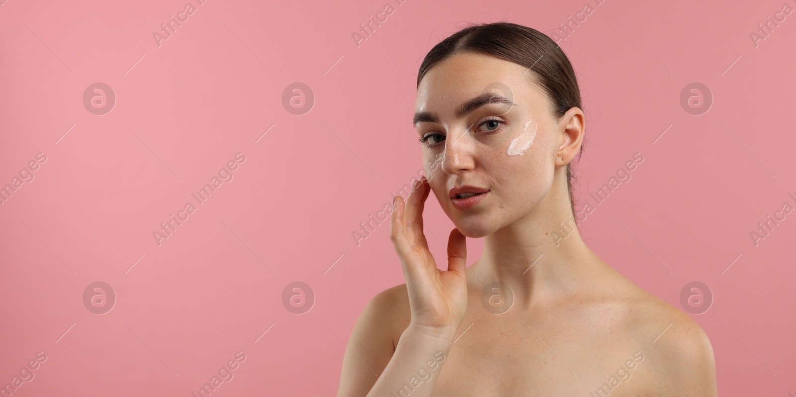 Photo of Beautiful woman with cream on her face against pink background