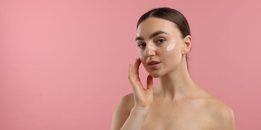 Photo of Beautiful woman with cream on her face against pink background