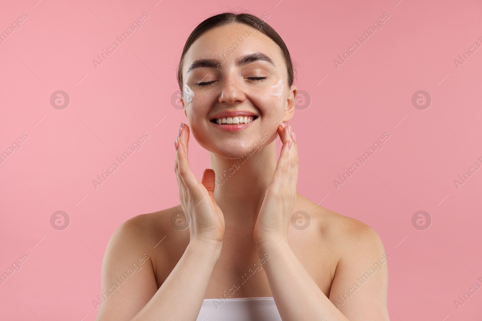 Photo of Beautiful woman with cream on her face against pink background