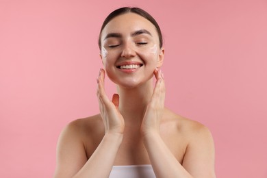 Photo of Beautiful woman with cream on her face against pink background