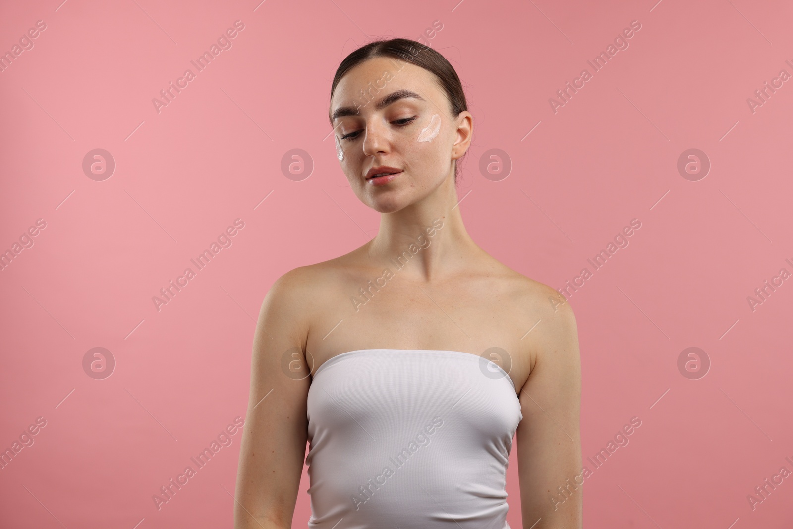 Photo of Beautiful woman with cream on her face against pink background