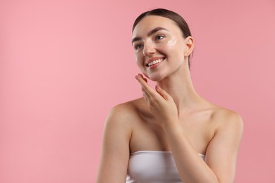 Photo of Beautiful woman with cream on her face against pink background. Space for text