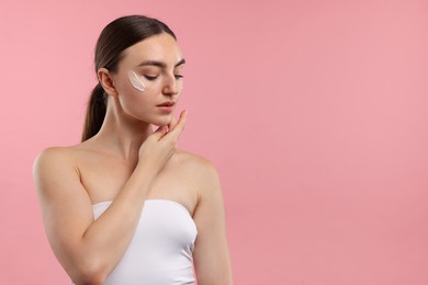 Photo of Beautiful woman with cream on her face against pink background. Space for text