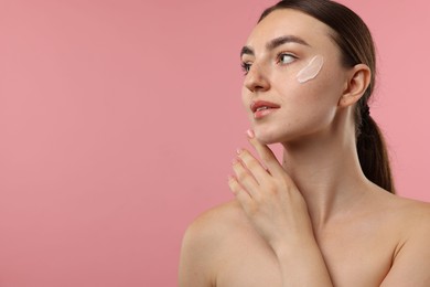 Photo of Beautiful woman with cream on her face against pink background. Space for text