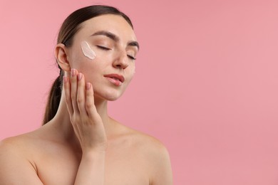 Photo of Beautiful woman with cream on her face against pink background. Space for text