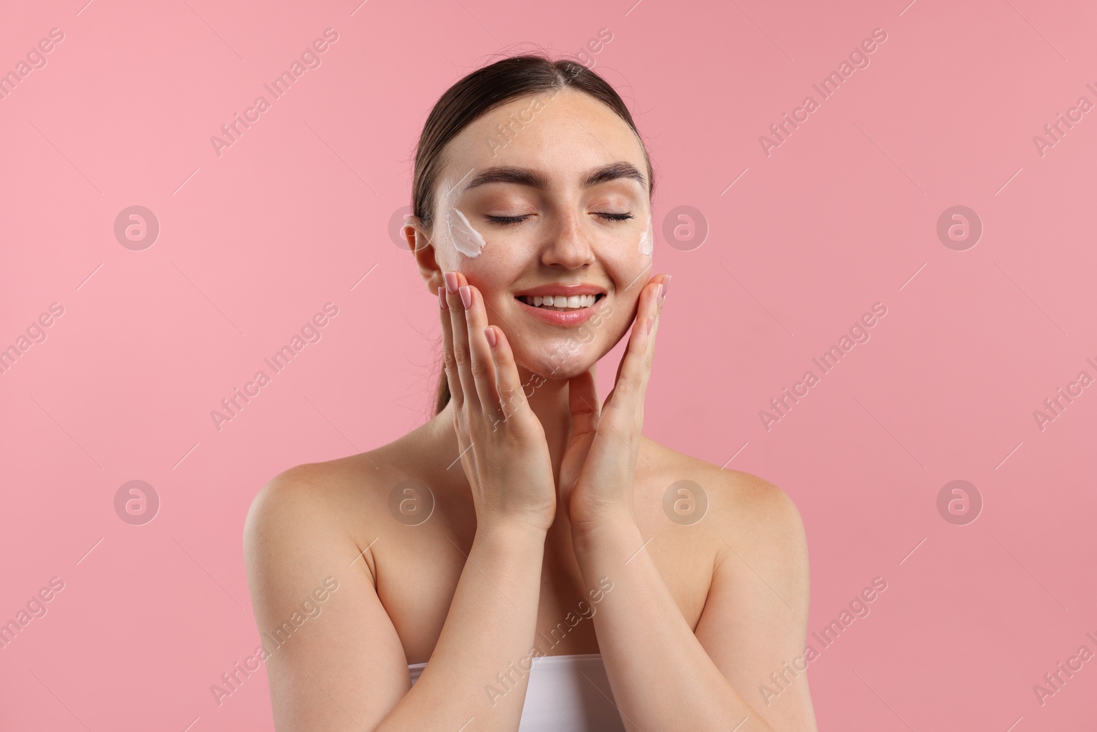 Photo of Beautiful woman with cream on her face against pink background