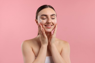 Photo of Beautiful woman with cream on her face against pink background