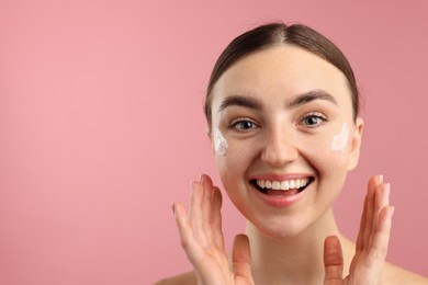 Photo of Beautiful woman with cream on her face against pink background. Space for text