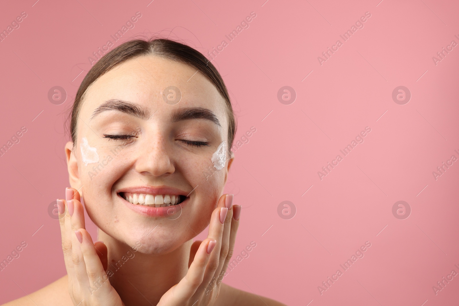 Photo of Beautiful woman with cream on her face against pink background. Space for text