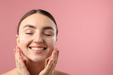 Photo of Beautiful woman with cream on her face against pink background. Space for text
