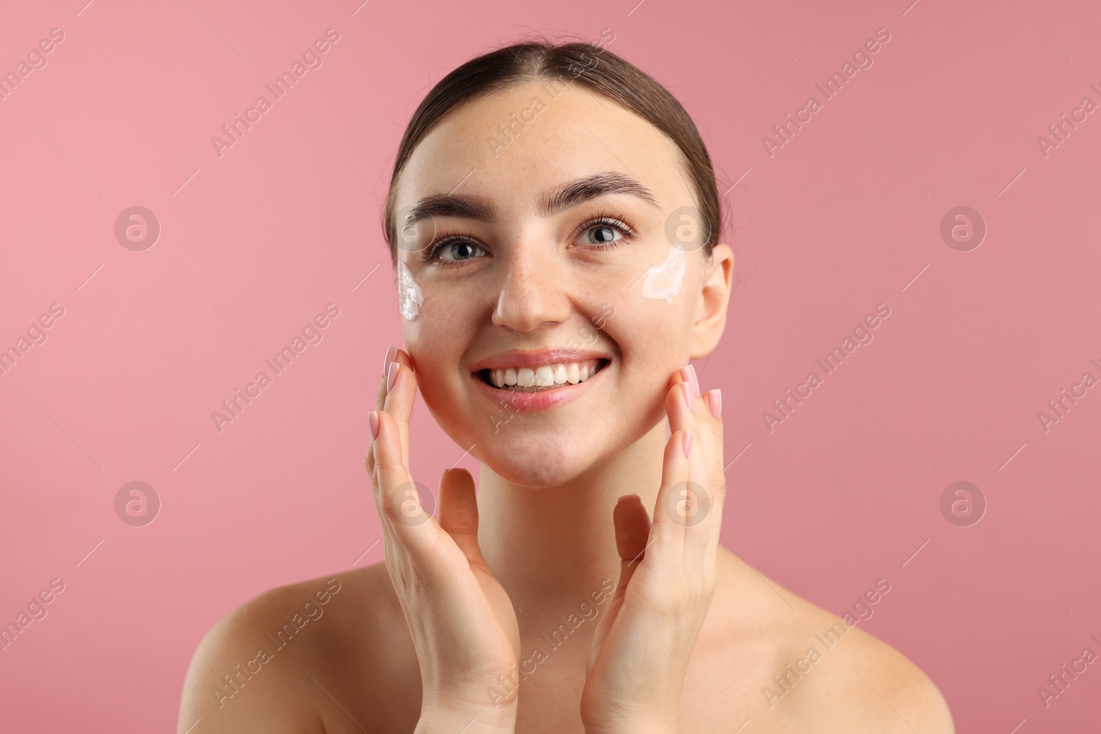 Photo of Beautiful woman with cream on her face against pink background