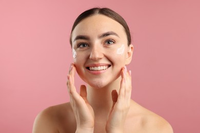 Photo of Beautiful woman with cream on her face against pink background