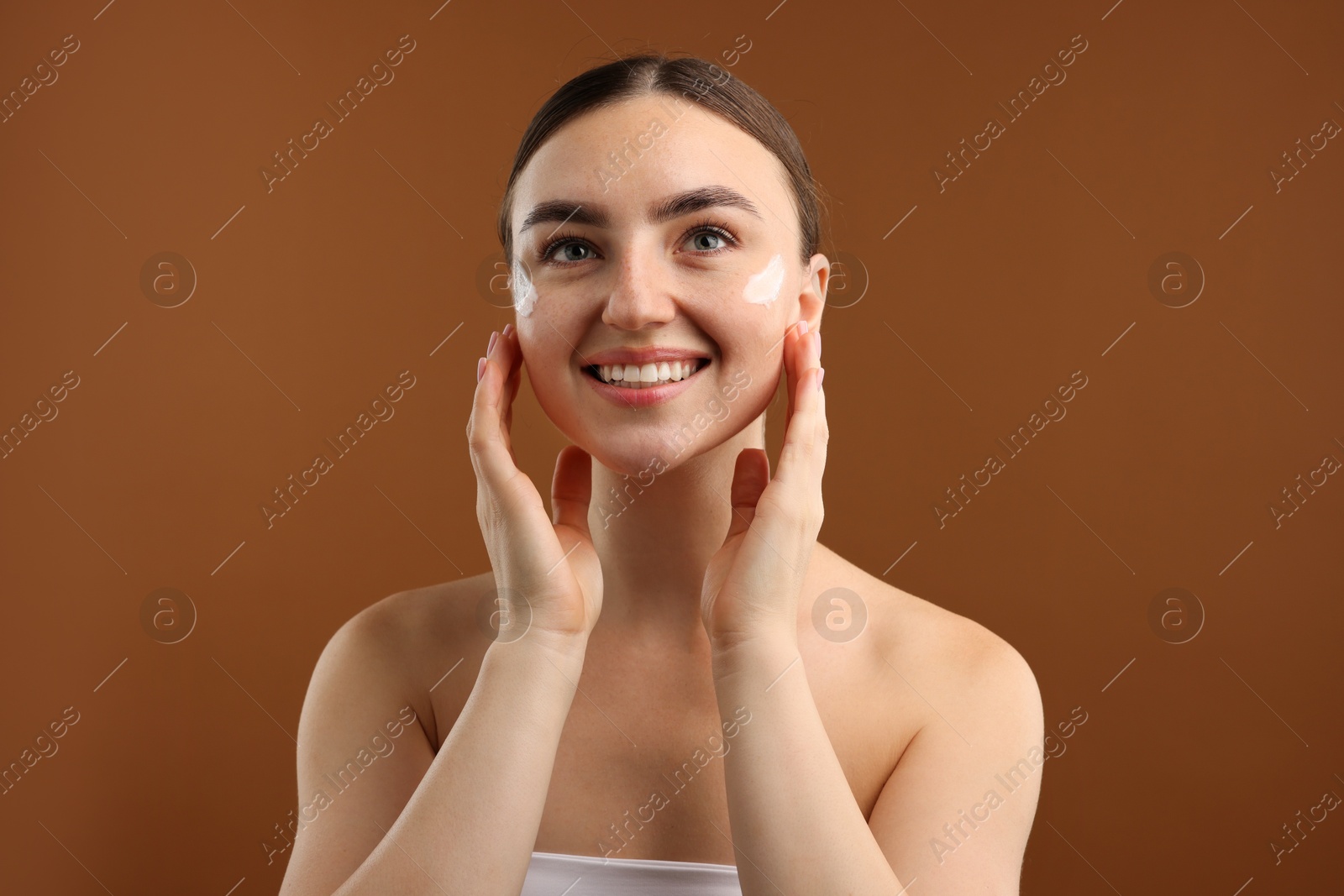 Photo of Beautiful woman with cream on her face against brown background