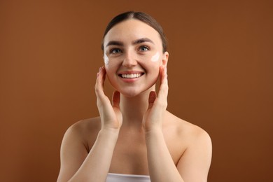 Photo of Beautiful woman with cream on her face against brown background