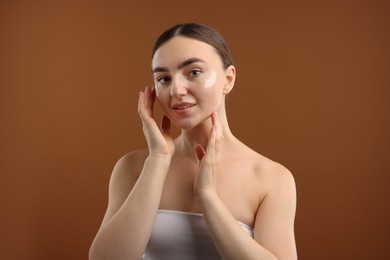 Photo of Beautiful woman with cream on her face against brown background