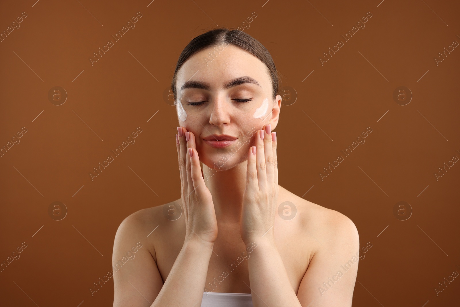 Photo of Beautiful woman with cream on her face against brown background
