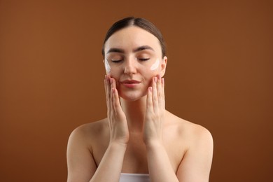 Photo of Beautiful woman with cream on her face against brown background