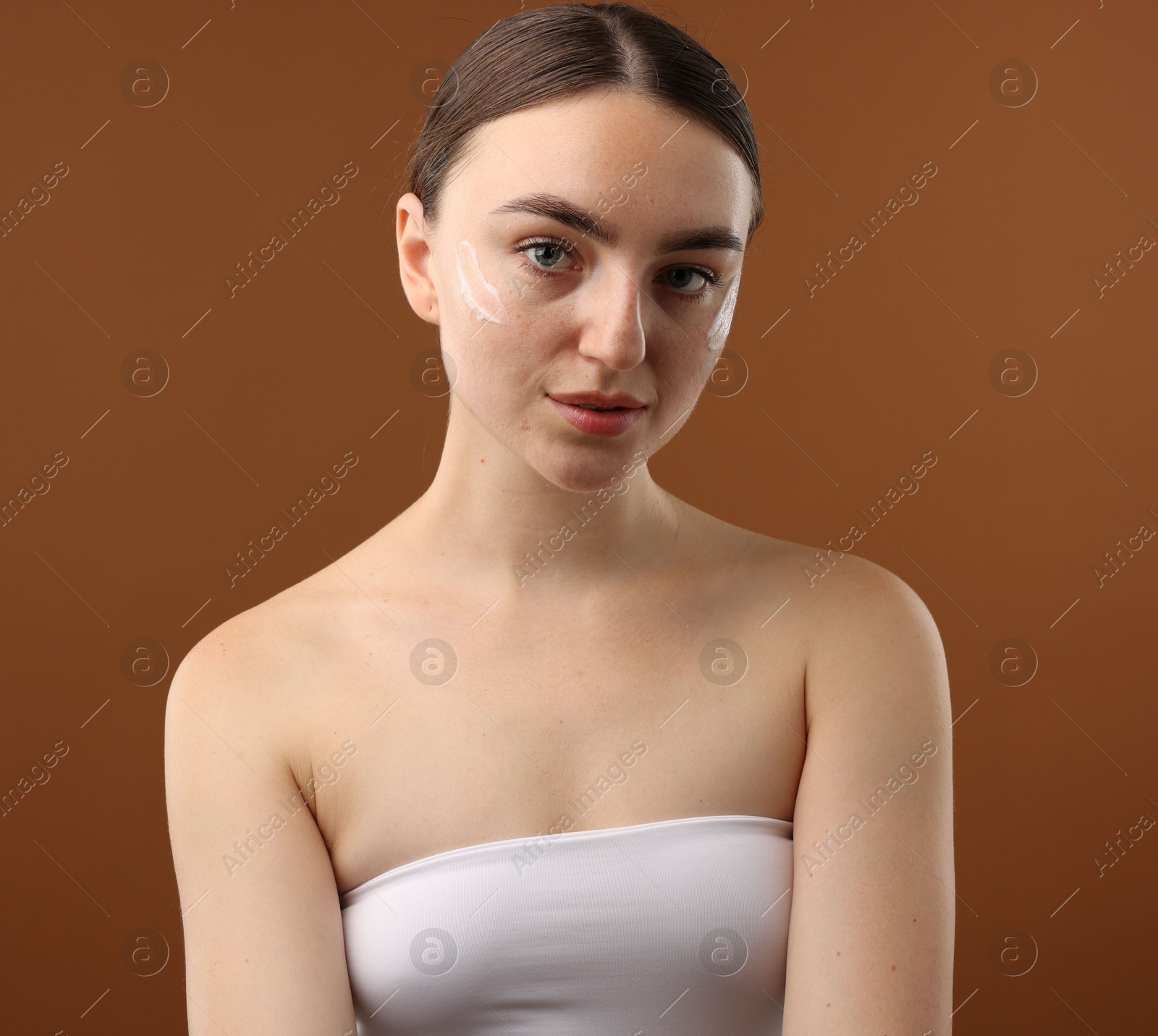 Photo of Beautiful woman with cream on her face against brown background