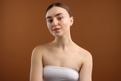 Photo of Beautiful woman with cream on her face against brown background