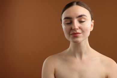 Photo of Beautiful woman with cream on her face against brown background. Space for text