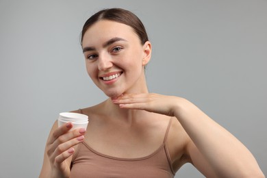 Photo of Beautiful woman with jar of face cream on gray background
