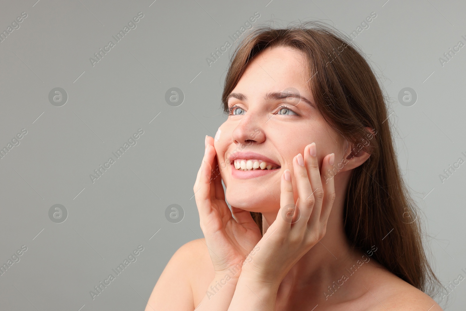 Photo of Beautiful woman with cream on her face against gray background. Space for text