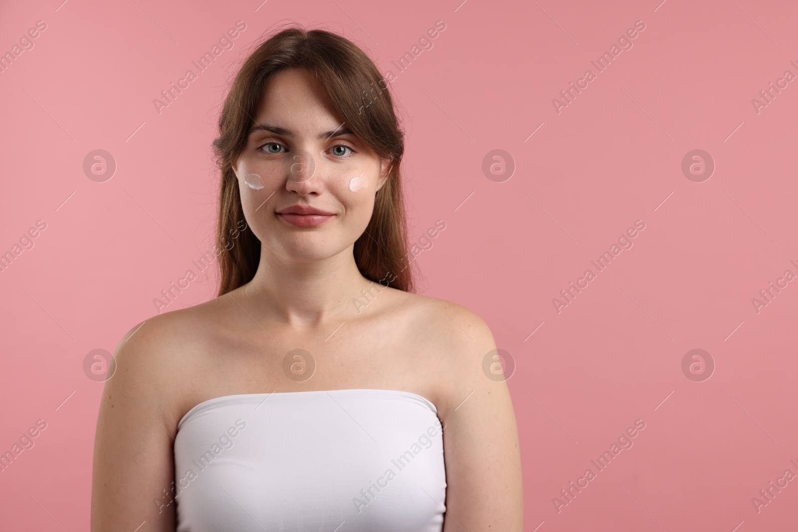 Photo of Beautiful woman with cream on her face against pink background. Space for text