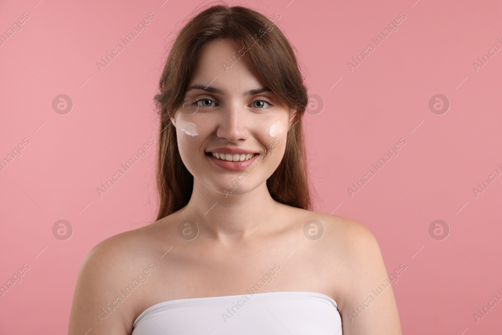 Photo of Beautiful woman with cream on her face against pink background