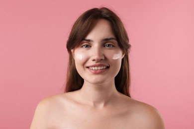 Photo of Beautiful woman with cream on her face against pink background