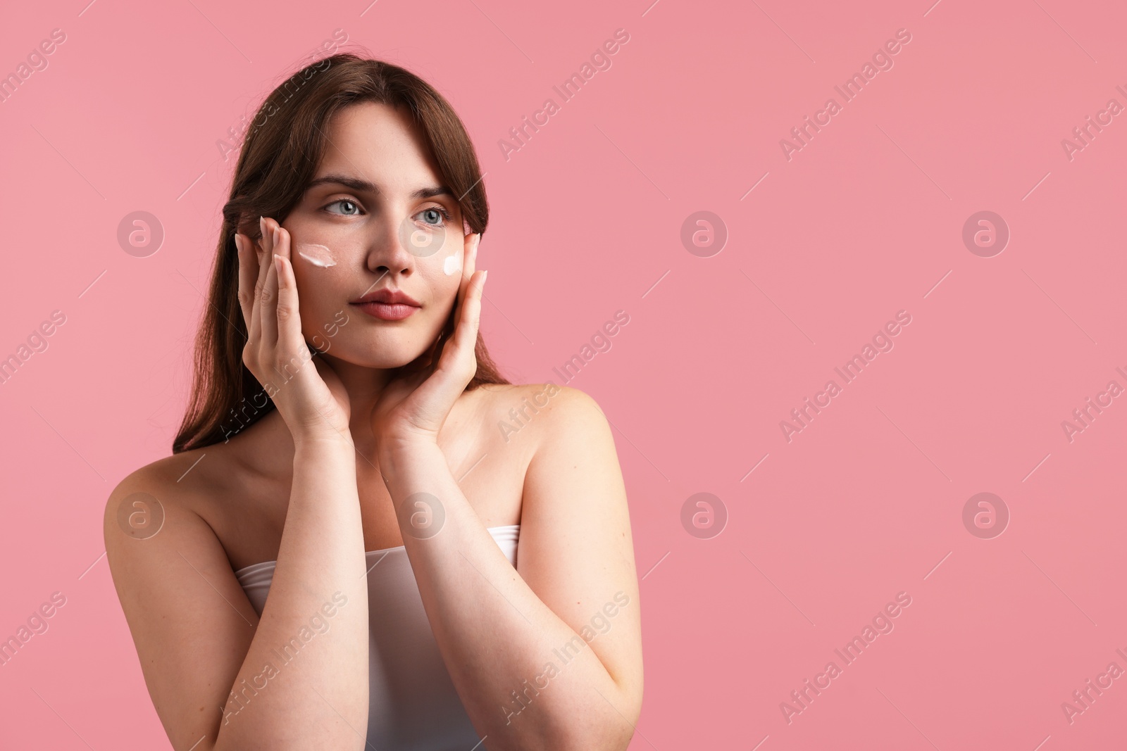 Photo of Beautiful woman with cream on her face against pink background. Space for text