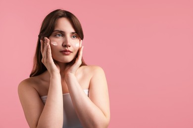Photo of Beautiful woman with cream on her face against pink background. Space for text