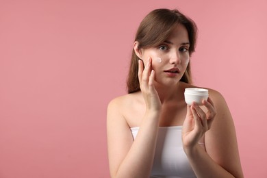 Photo of Beautiful woman with jar of face cream on pink background. Space for text