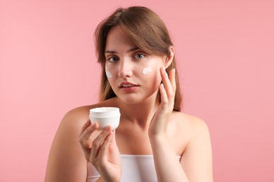 Photo of Beautiful woman with jar of face cream on pink background