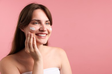 Photo of Beautiful woman with cream on her face against pink background. Space for text