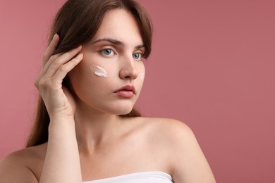 Photo of Beautiful woman with cream on her face against pink background. Space for text