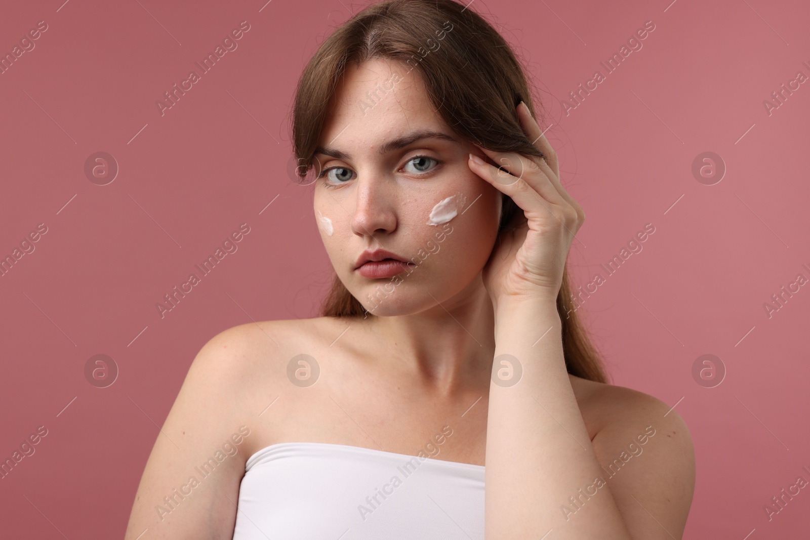 Photo of Beautiful woman with cream on her face against pink background