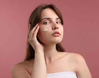 Photo of Beautiful woman with cream on her face against pink background