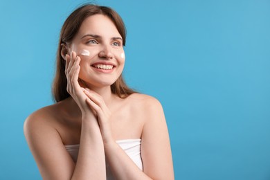 Photo of Beautiful woman with cream on her face against light blue background. Space for text