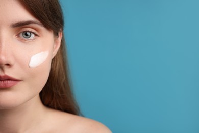 Photo of Beautiful woman with cream on her face against light blue background, closeup. Space for text