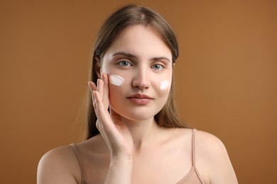 Photo of Beautiful woman with cream on her face against brown background