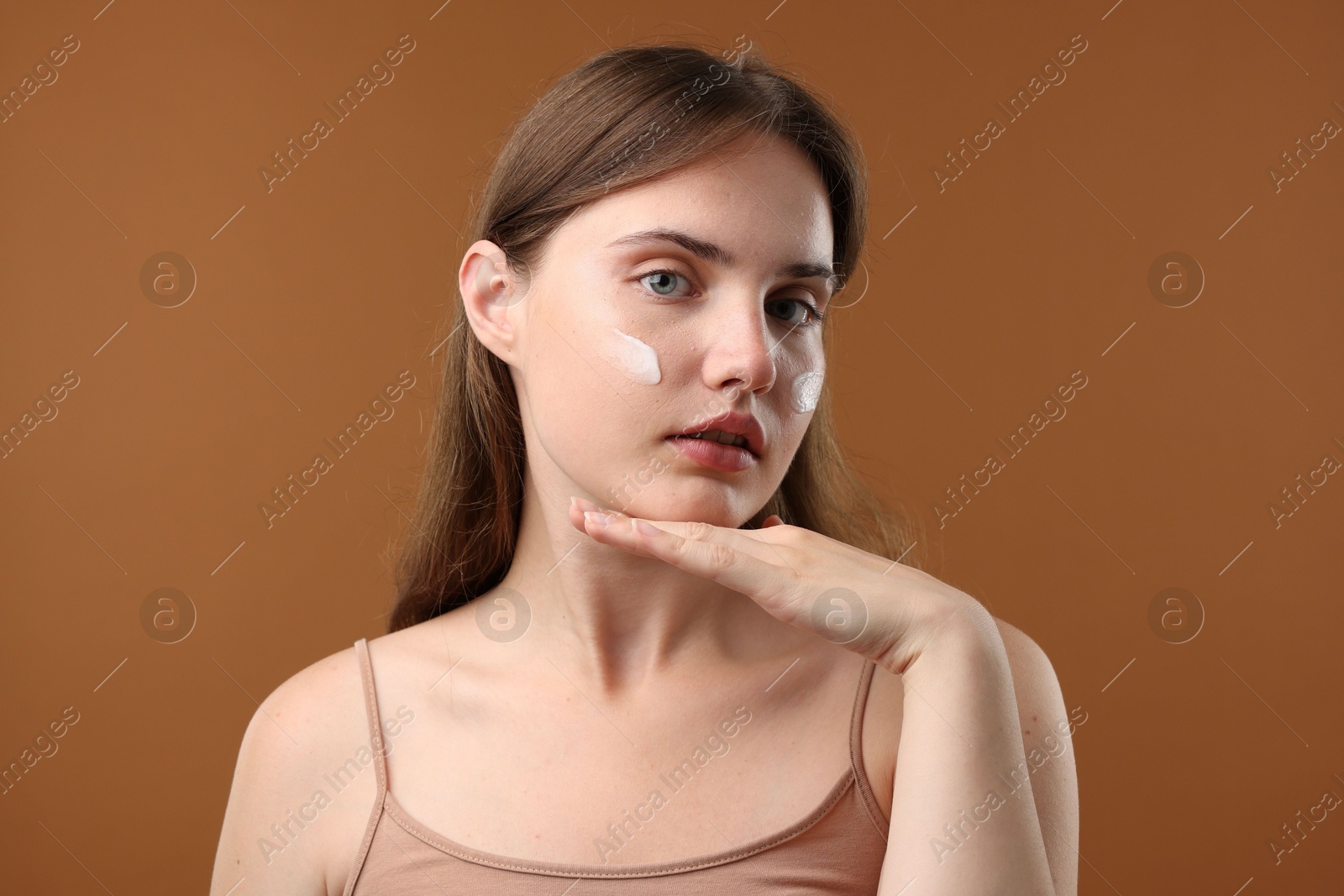 Photo of Beautiful woman with cream on her face against brown background