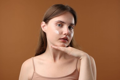 Photo of Beautiful woman with cream on her face against brown background